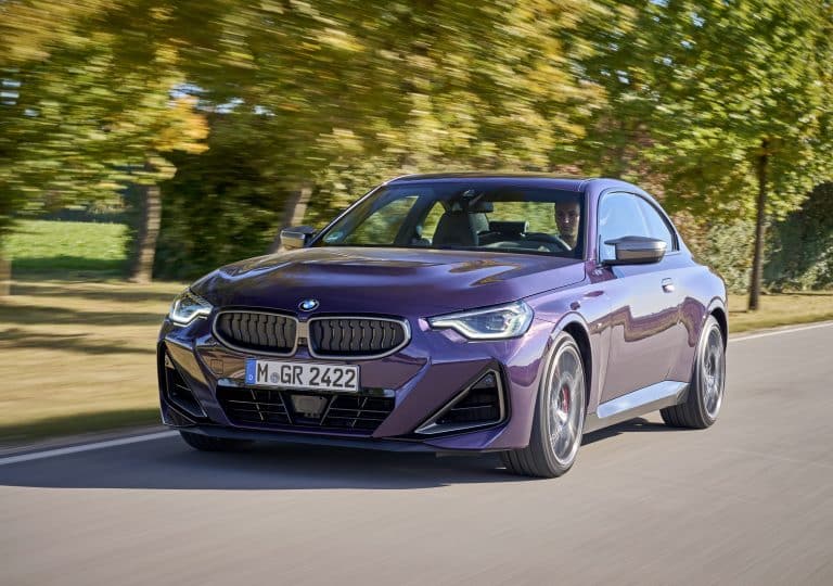 BMW Serie 2 Coupé violette roulant sur une route de campagne