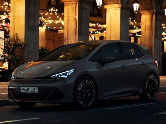 Cupra Born grise devant un hôtel illuminé pour faire ressortir le côté mystérieux de cette voiture