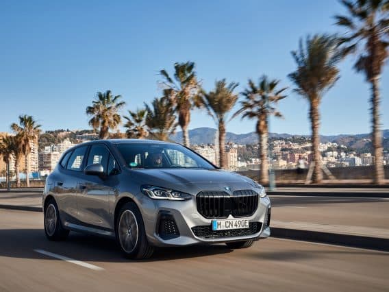 BMW Série 2 Active Tourer roulant sur une route bordée de palmiers sous un ciel bleu
