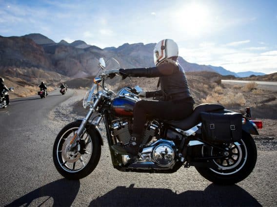 motard conduisant une Harley Davidson sur une route avec un groupe de motards