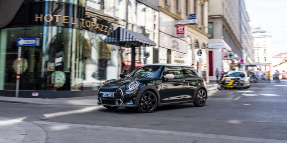 mini d'occasion roulant en centre ville et passant devant un hôtel