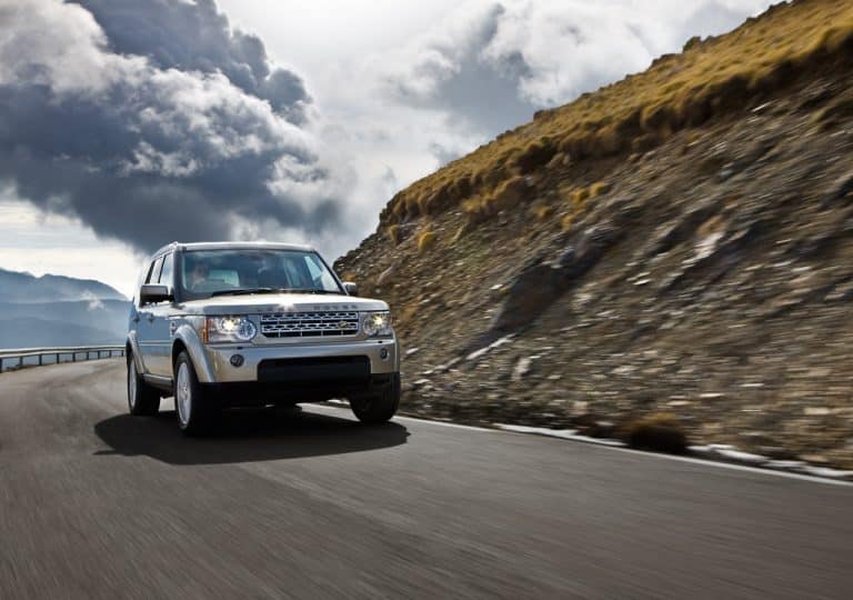 Land Rover Discovery 4e generation roulant sur une route de montagne avec les phares allumés